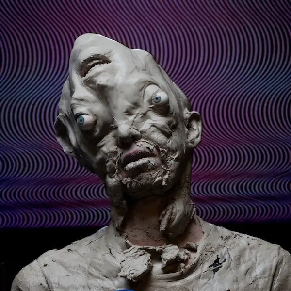 A clay-sculpted head against a backdrop of purple wave lines