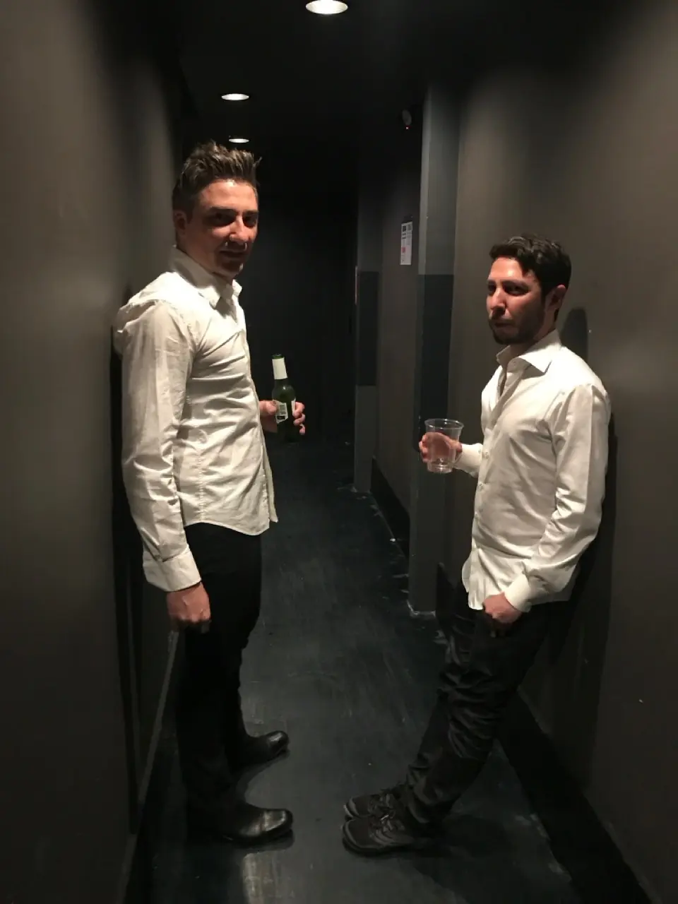 Two men in white shirts in a dark corridor before a Black Line show in Los Angeles