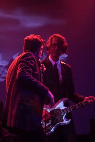 A bassist and a singer on a red-lit stage