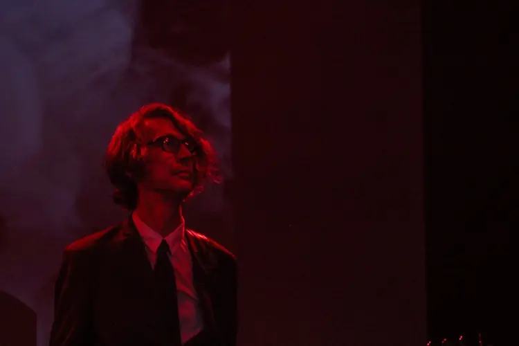 A performer in red light on a dark stage