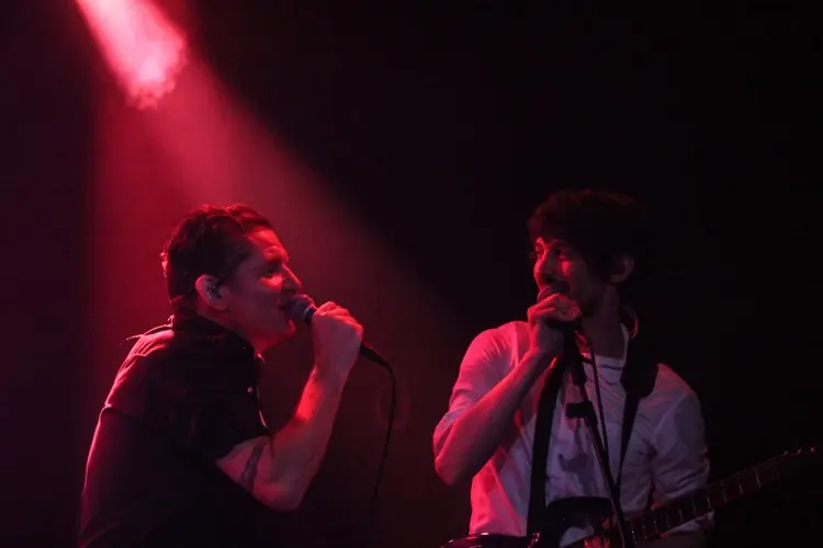 Two singers sharing a red-lit stage