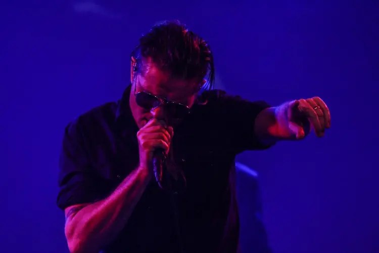 A singer gesturing against a deep blue backdrop