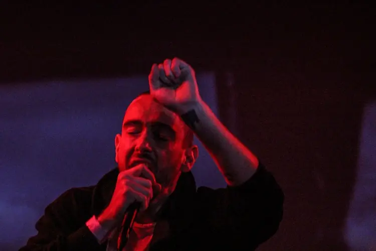 A singer with a hand raised, lit red