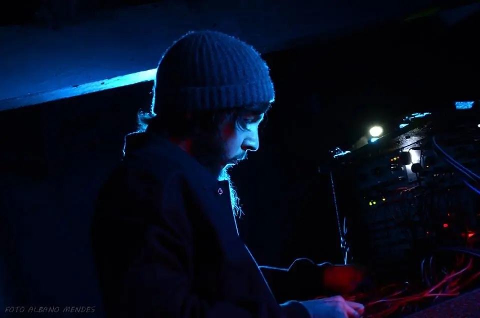A performer in a beanie at a rig in blue light