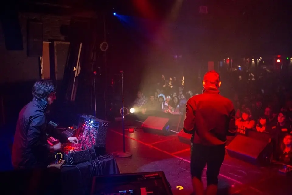 A red-lit stage and crowd seen from the side