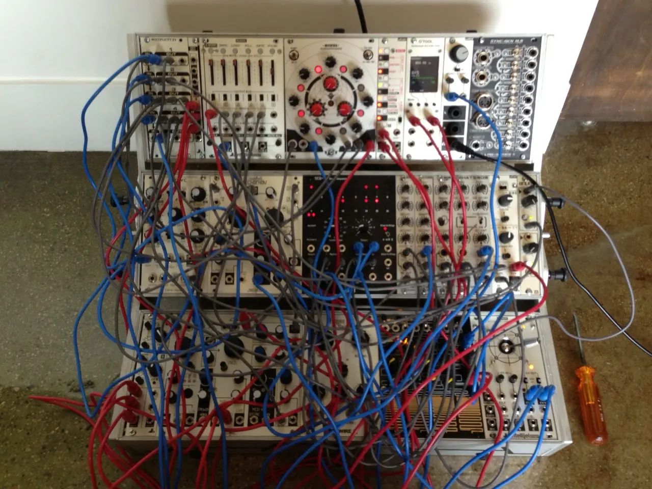 The live rig: a silver modular synth on the floor, patched with blue, red and grey cables