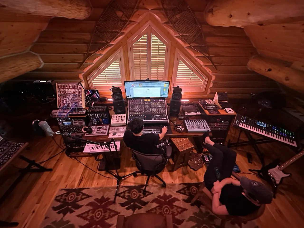 The Montana log-cabin studio in red light, two people at work