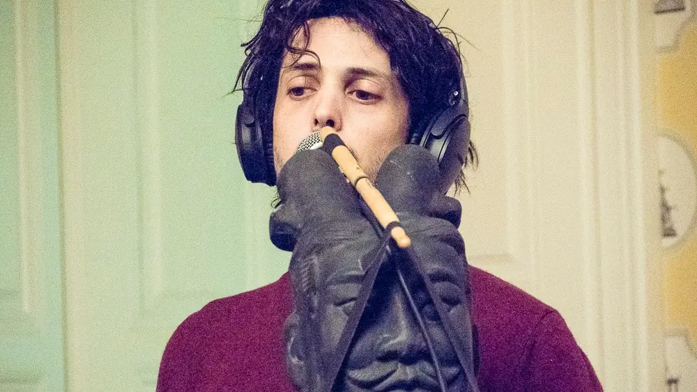 A man in headphones holding a microphone in a gloved hand