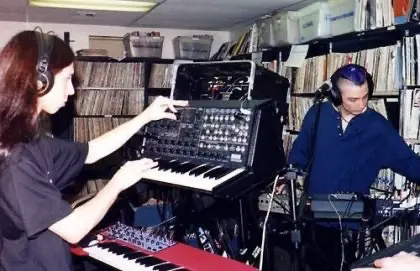 Annodalleb live on KUCI radio: two people playing synths in a room lined with records