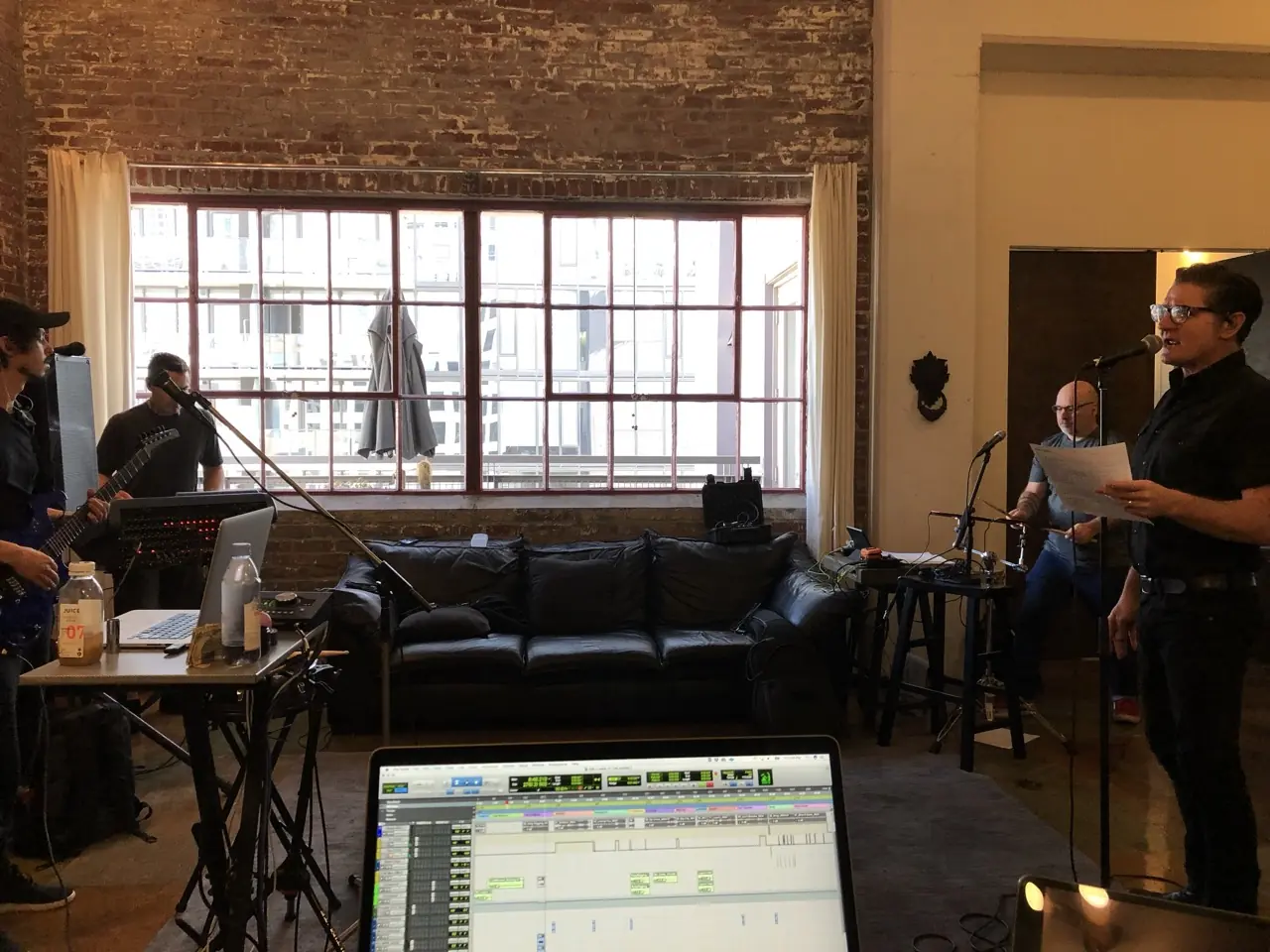 A band rehearsing in a brick loft, a laptop running the session in the foreground