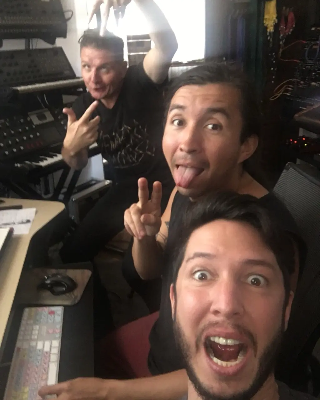 Three men pulling faces in a studio selfie