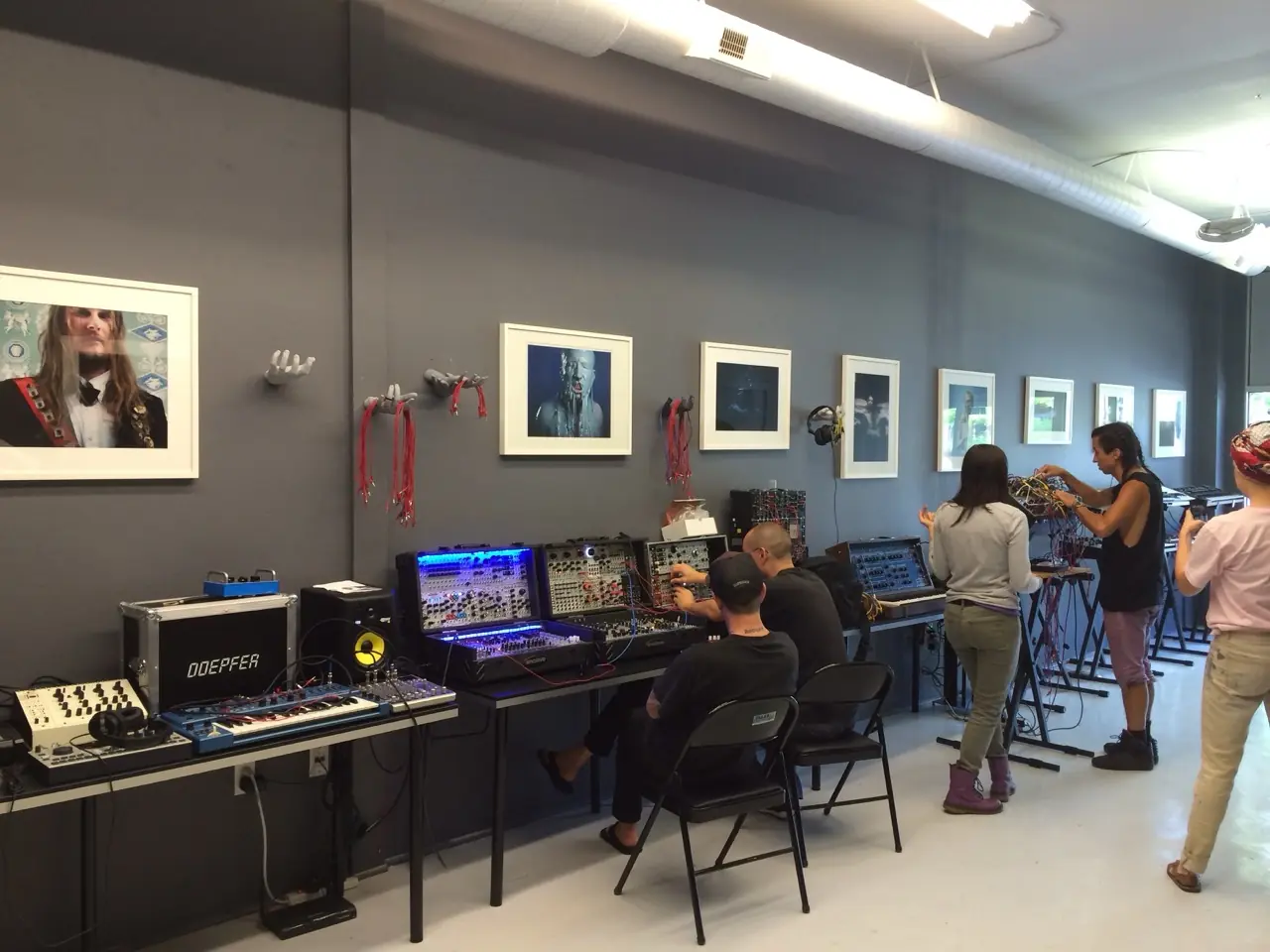 Synths and modular cases set out on tables, people playing them