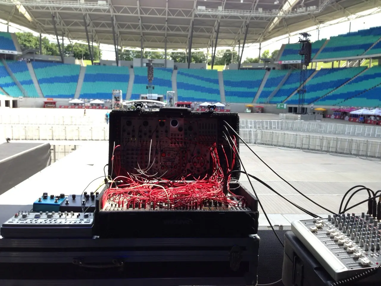 A suitcase modular patched with red cables on a stage in an empty stadium